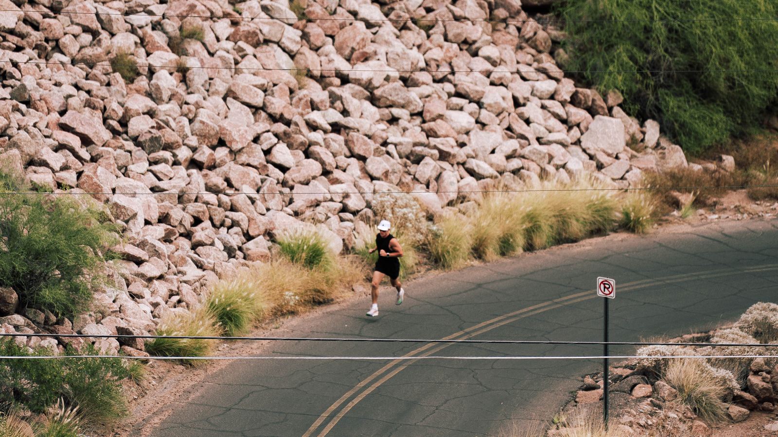 A runner on a rocky desert road at the base of a Phoenix mountain